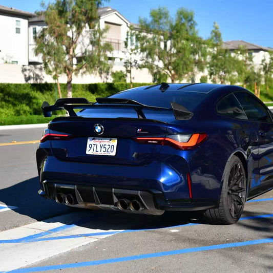 Blue BMW G82 M4 parked on a street with residential buildings in the background. Euro MP Style Carbon Fiber Rear Diffuser Installed.